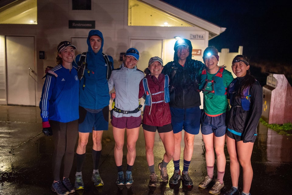 Seven runners lined up with rain gear and all but one in shorts in front of the Rodeo Beach bathrooms in the dark.