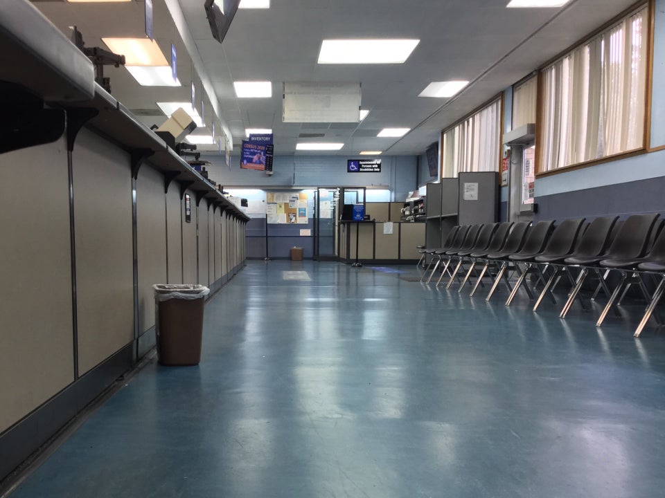 Indoors, no lines at the counters, empty seats in a waiting area to the right, signs above indicating which counter and line to go to for what.